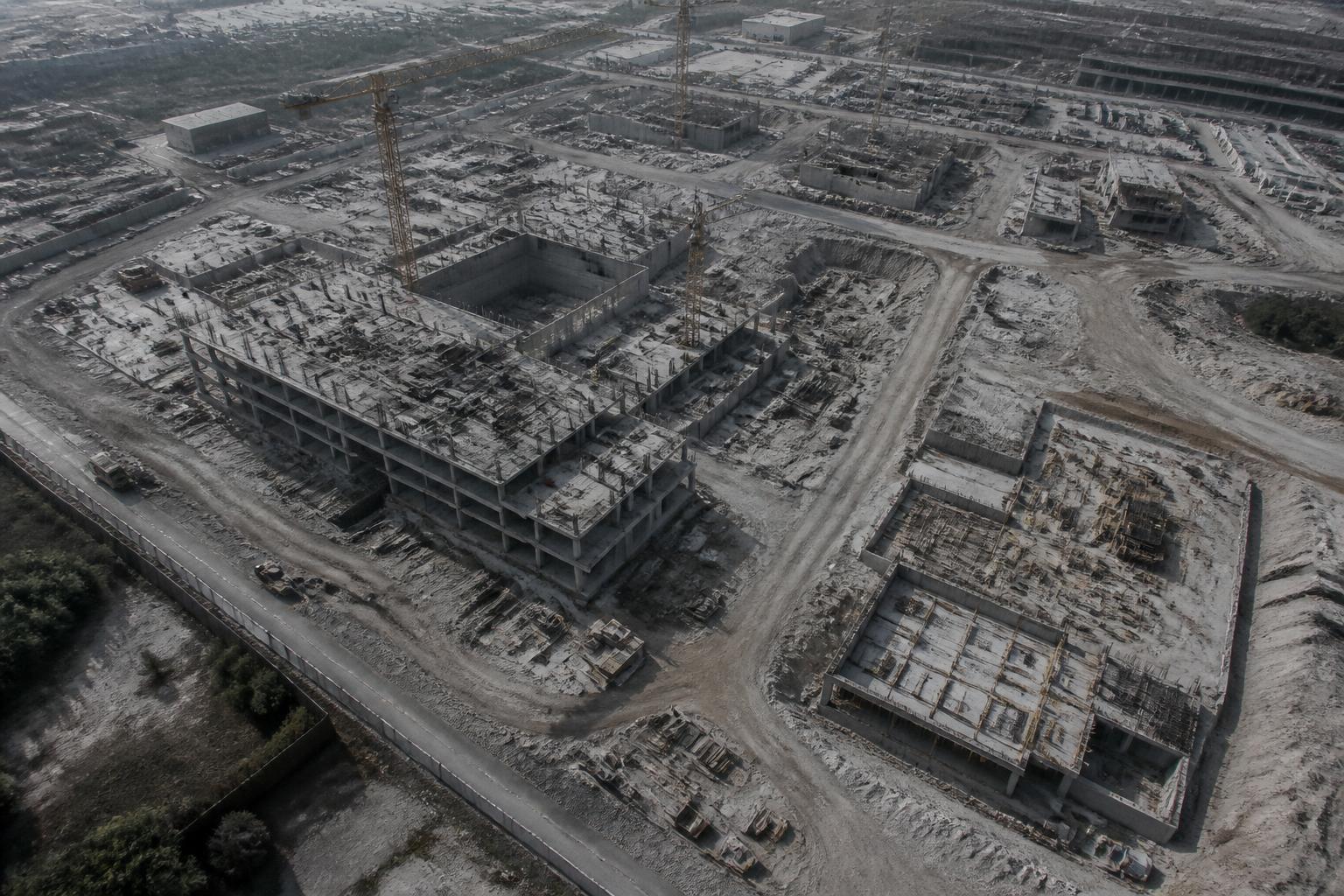 Oblique aerial view of an active construction site with unfinished structures, groundwork and access roads
